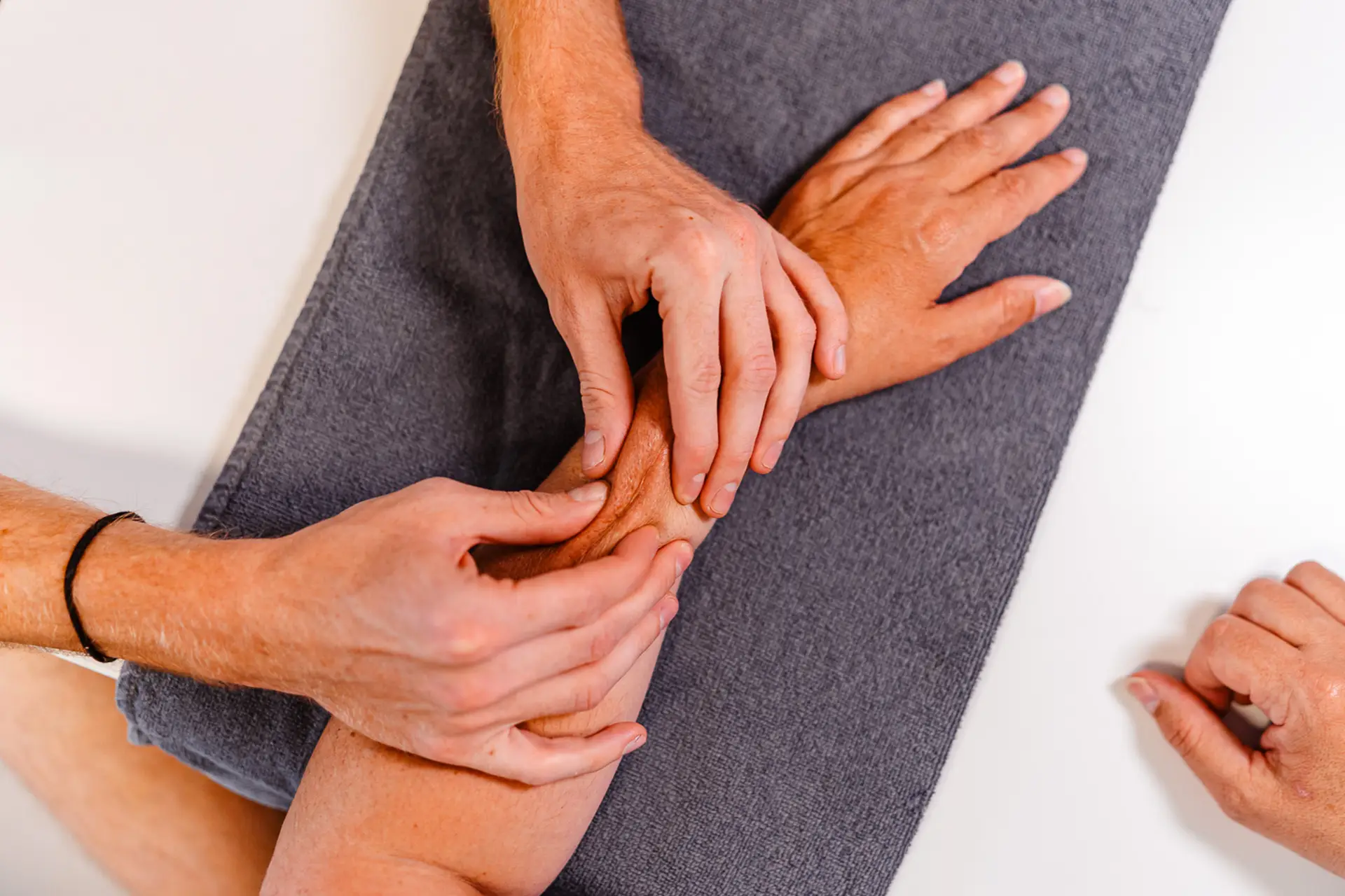 Nahaufnahme einer ergotherapeutischen Behandlung, bei der sanft Druck auf den Arm des Patienten ausgeübt wird, um Beweglichkeit und Heilung zu fördern. Ergotherapie in Augsburg.