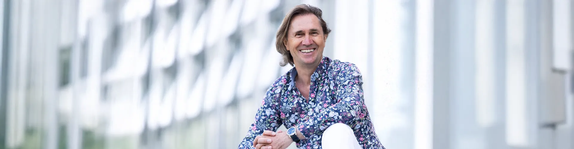 Bernhard Köck lächelt in einer modernen Umgebung und steht für transzendentale Meditation.