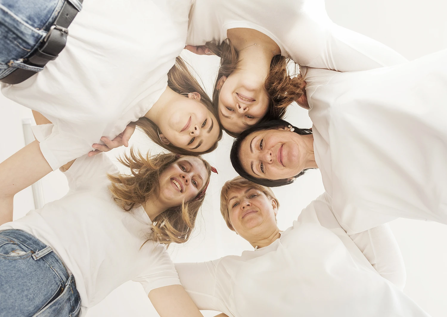 Fünf Frauen verschiedener Generationen blicken lächelnd in die Kamera; Symbol für Frauengesundheit und Epigenetik.